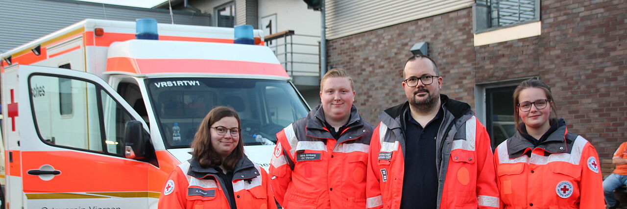Helfende des Sanitätsdienstes vor einem Rettungswagen