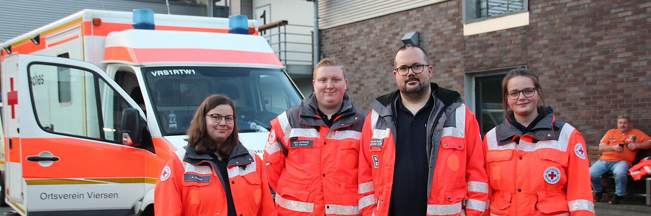 Helfende des Sanitätsdienstes vor einem Rettungswagen